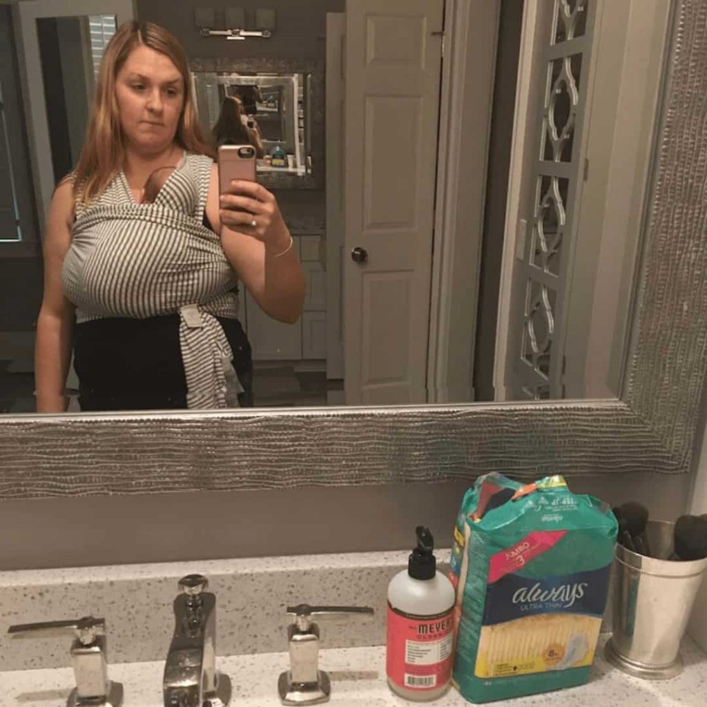 woman-taking-picture-in-bathroom-mirror-showing-her-wearing-her-baby-in-a-wrap-with-maxi-pads-sitting-in-front-of-mirror