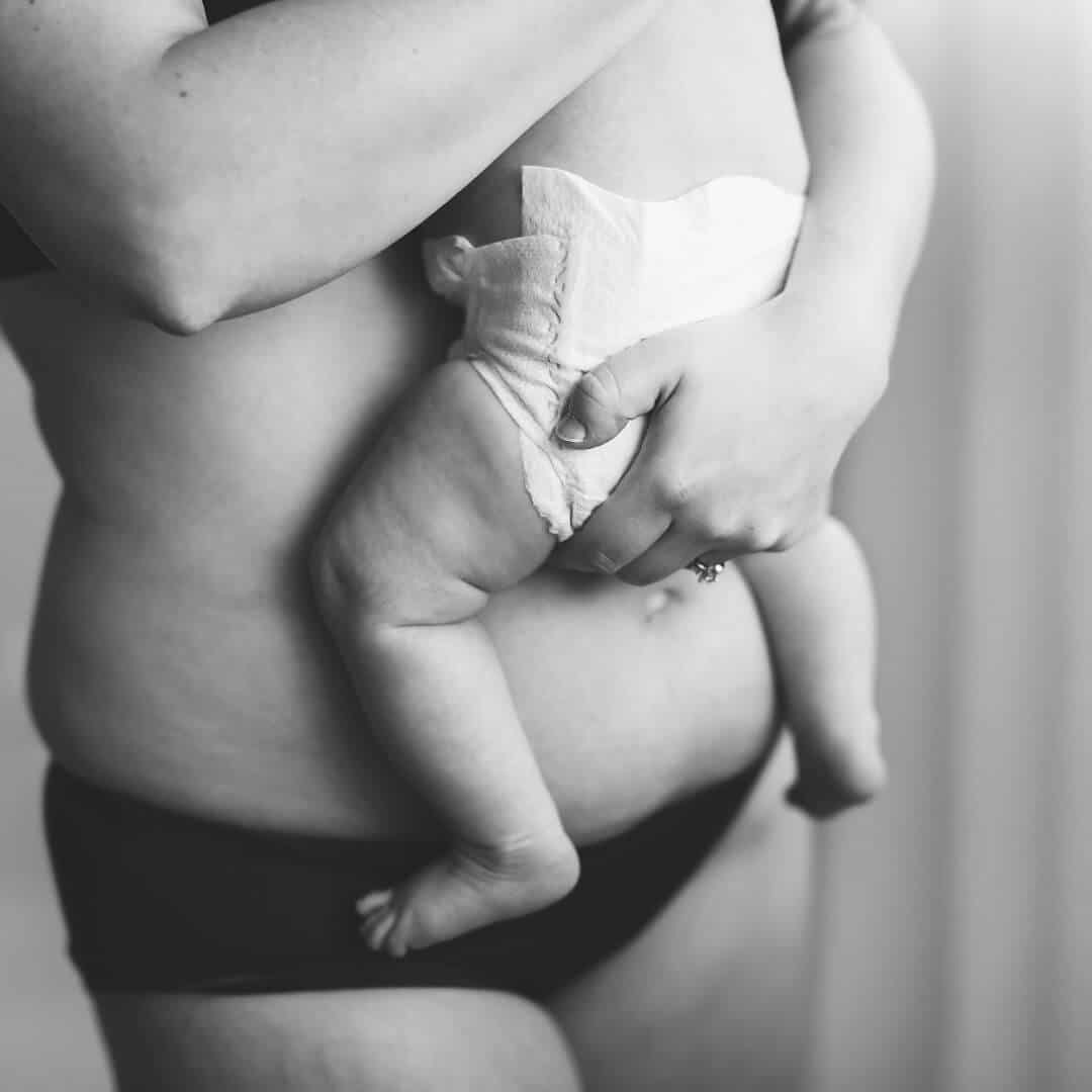 postpartum-mom-holding-new-baby-against-her-belly