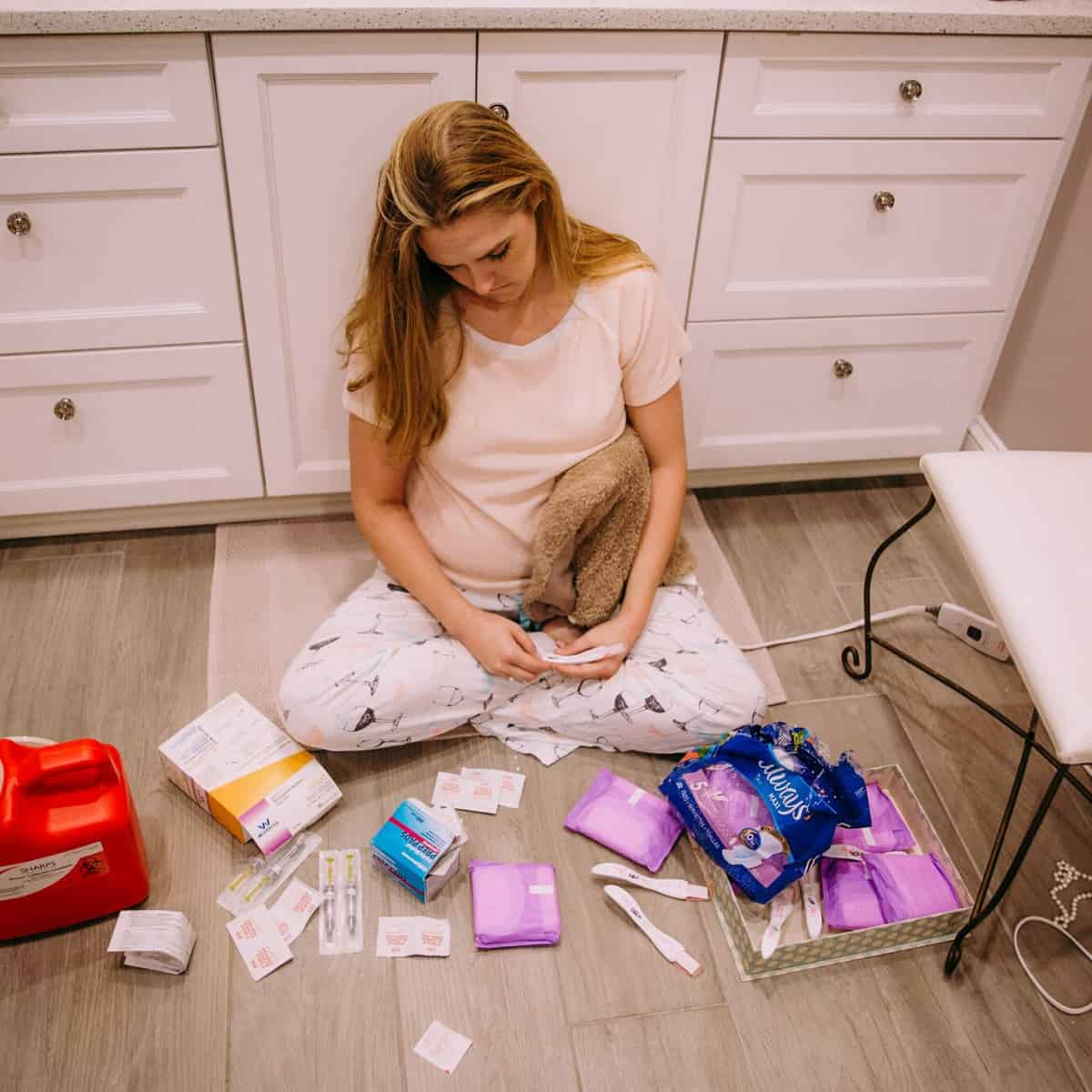 woman-on-floor-mourning-miscarriage-with-various-supplies-around-her