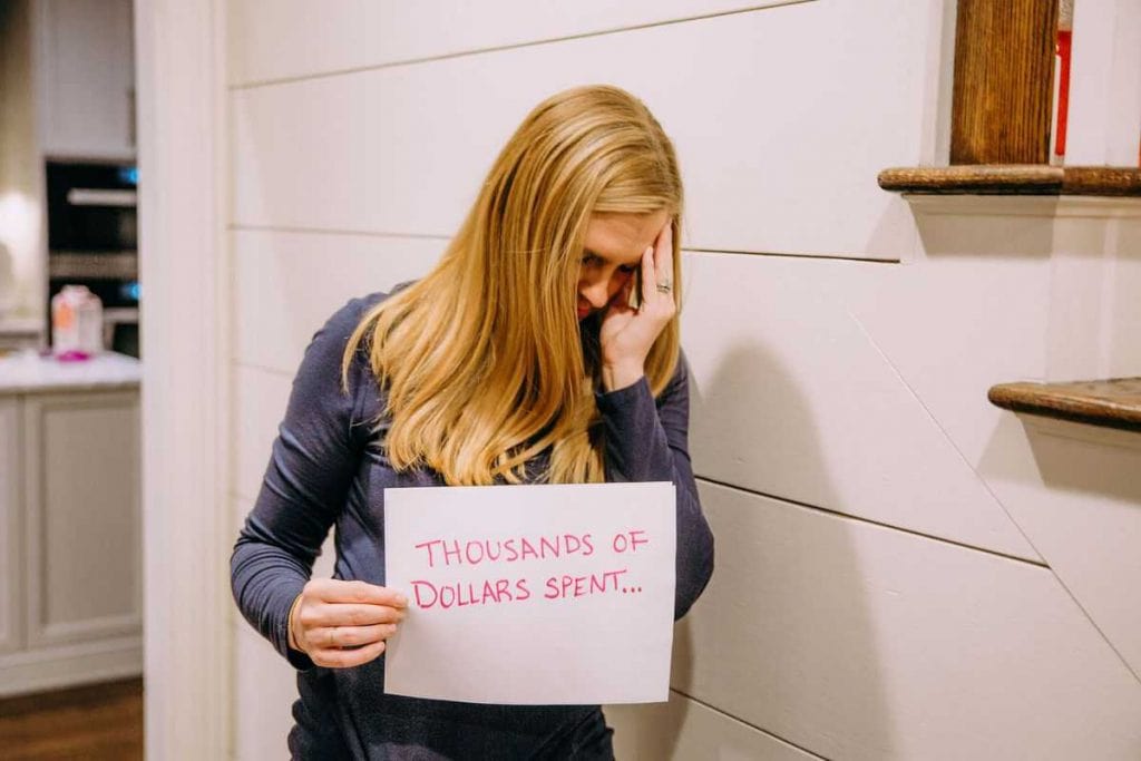 blonde-woman-with-head-in-hand-holding-sign-that-says-thousands-of-dollars-spent
