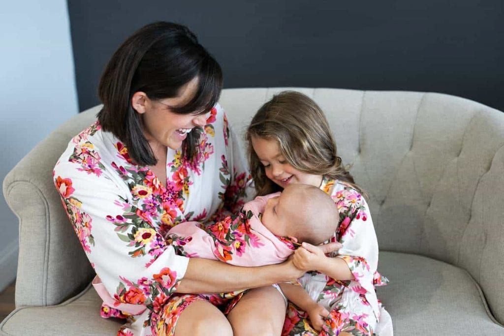 mother-holding-newborn-with-young-child-in-matching-floral-postpartum-pajamas