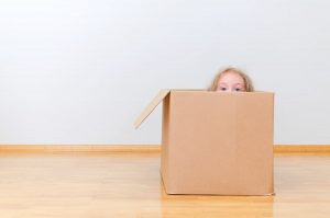 child hiding in moving box