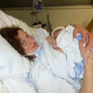 new-mom-in-hospital-bed-holding-new-baby