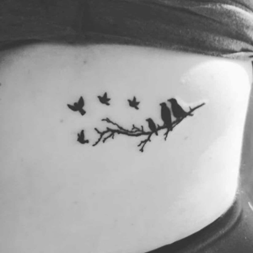 black tattoo of birds shows family sitting on branch while 4 birds fly away to represent 4 family members lost to miscarriage