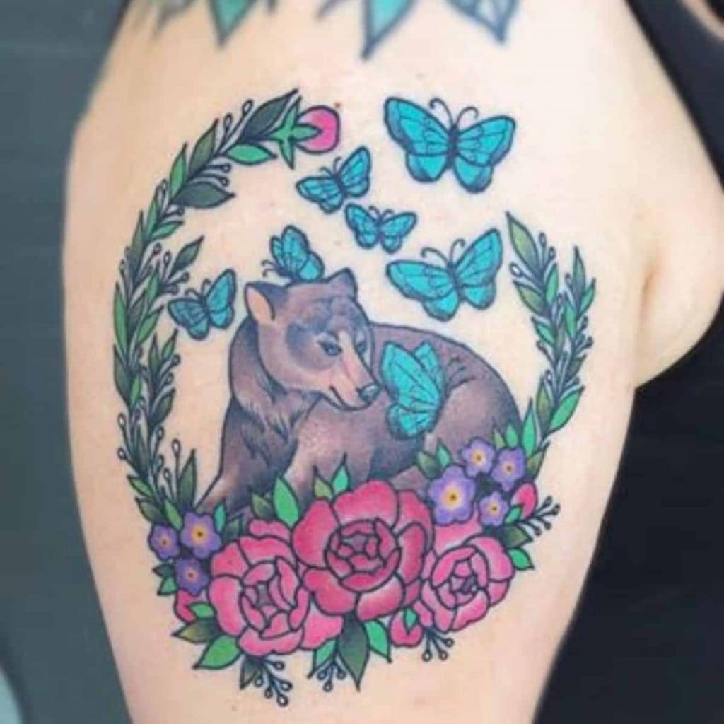 mama bear tattoo shows bear surrounded by butterflies and flowers to symbolize multiple miscarriages