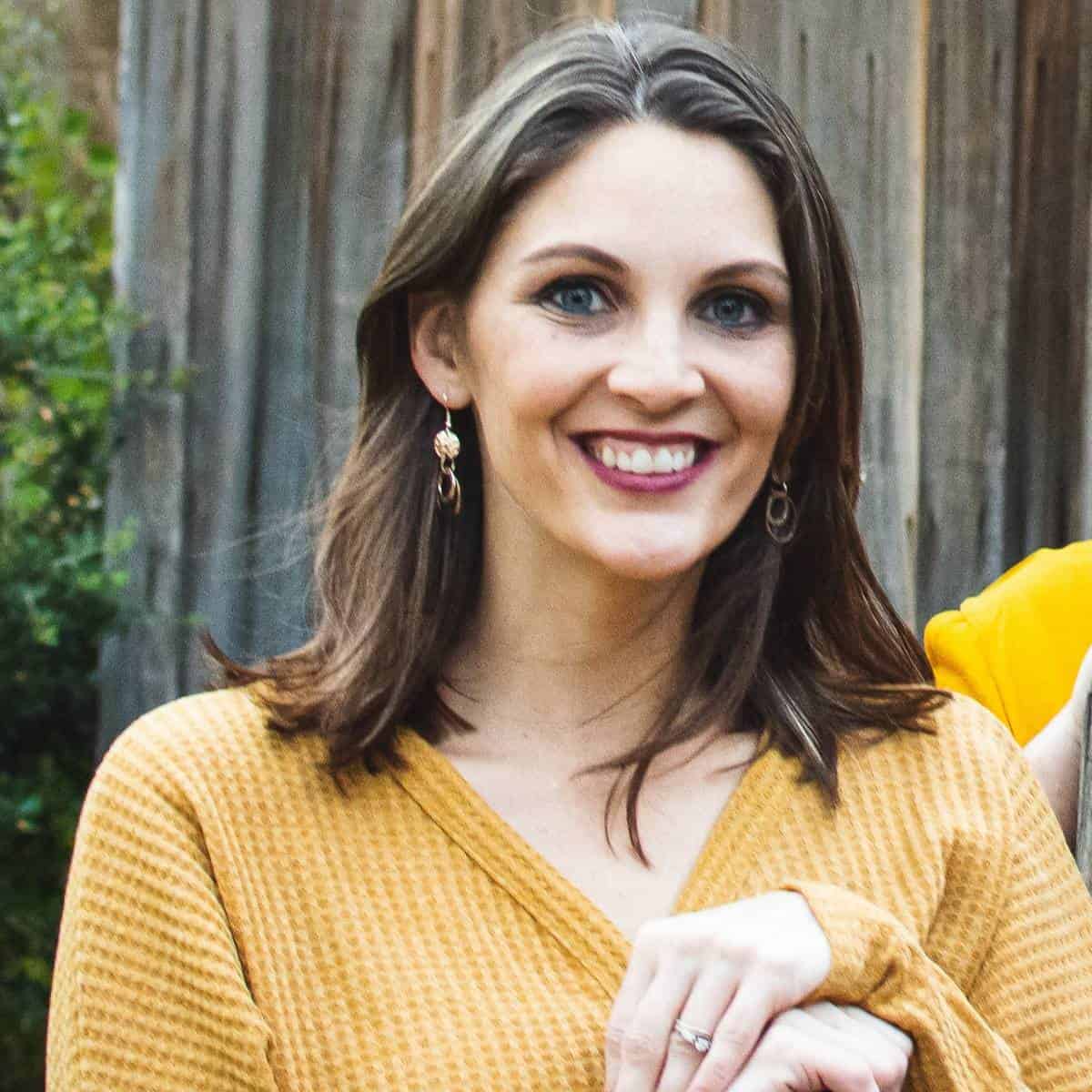 brunette woman in yellow sweater similing