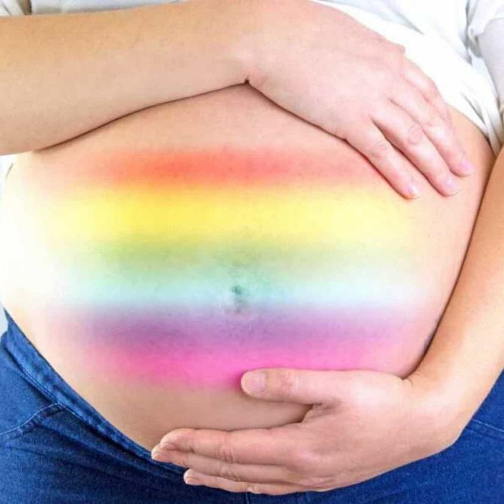 Pregnant belly with rainbow colors that represent a rainbow baby