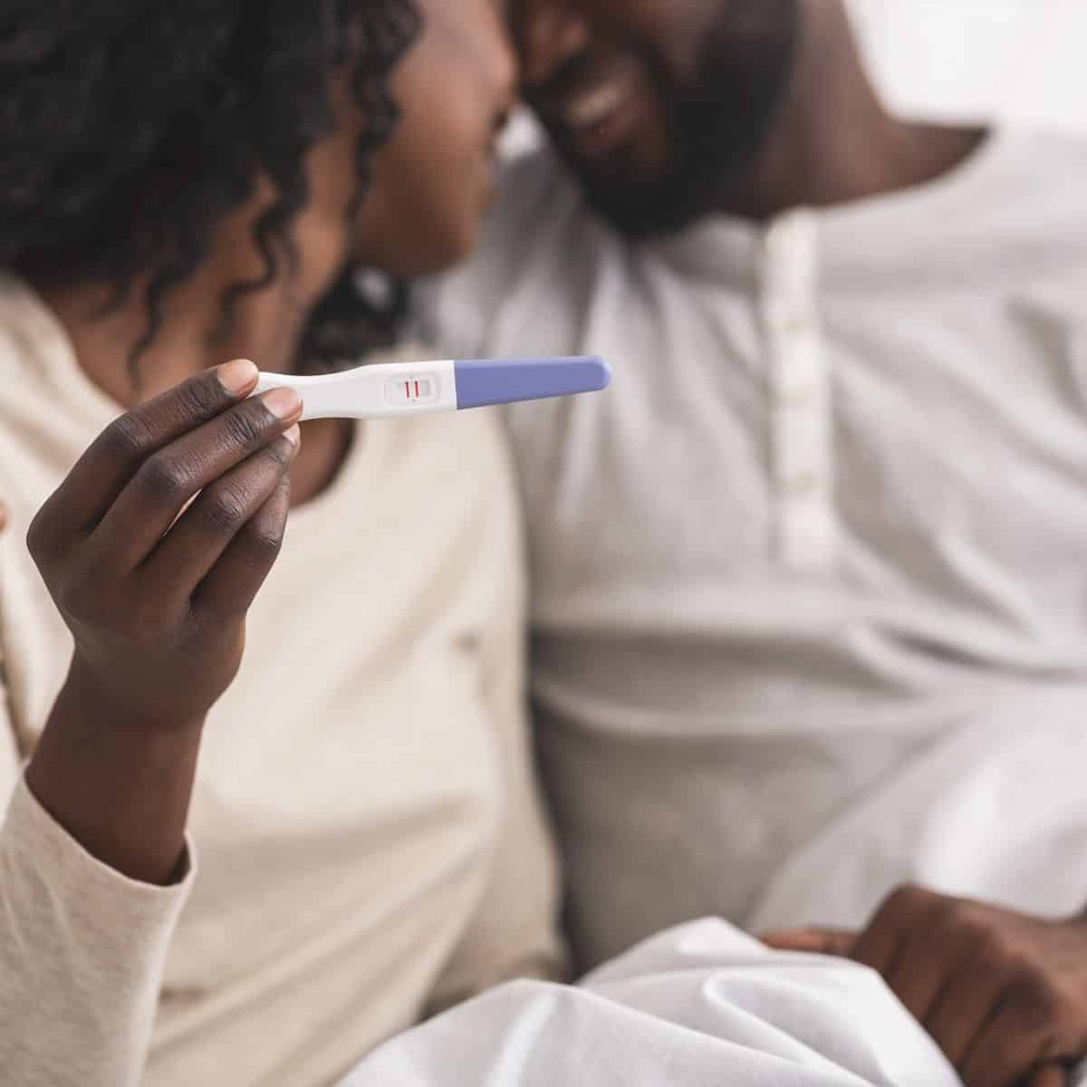 happy couple holding up a positive pregnancy test