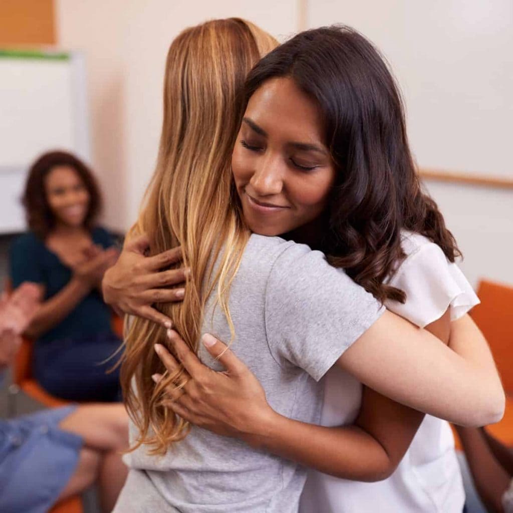 two friends hugging during a support group meeting