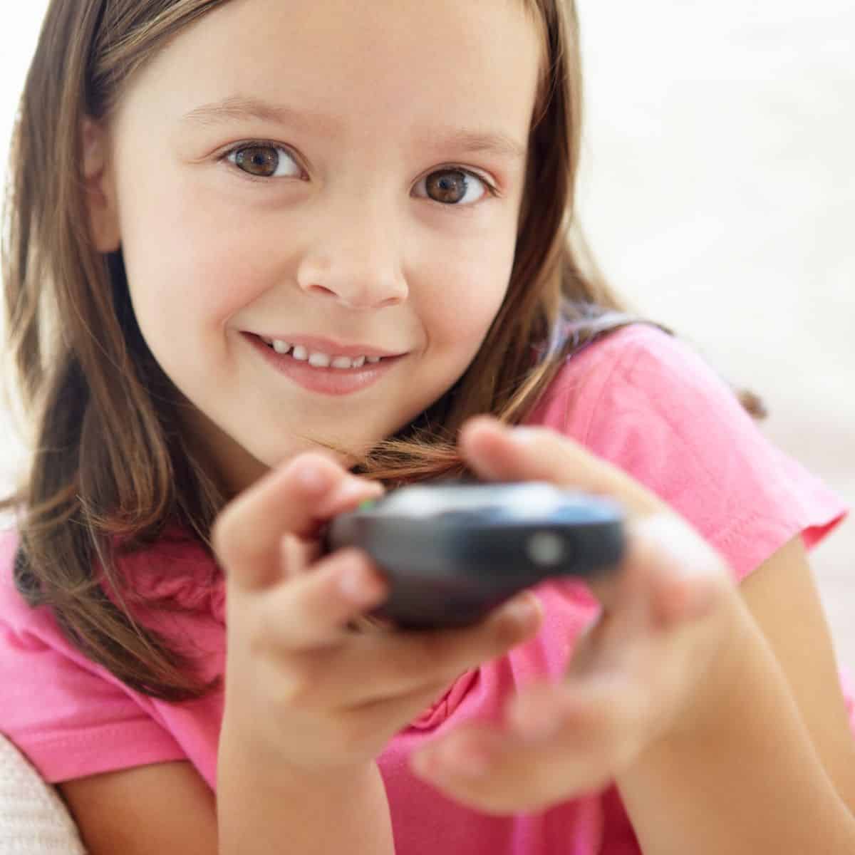 Little girl smiling while holding remote control for television