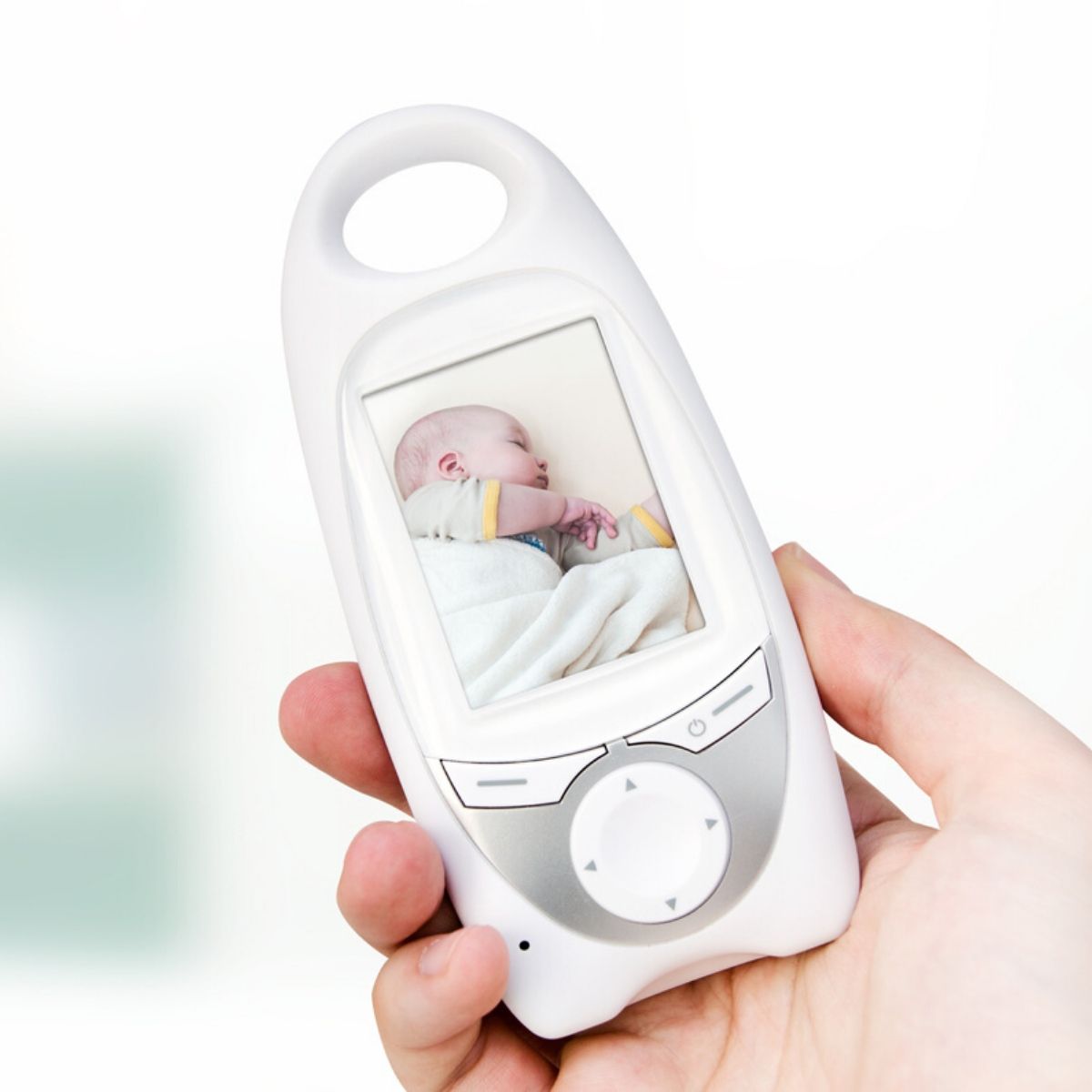 woman's hand holding up a baby monitor with an image of an infant on the monitor