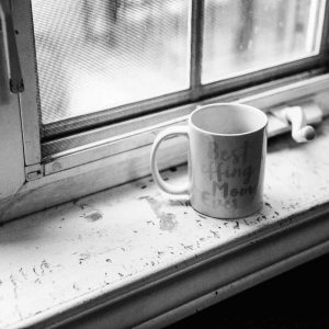 black and white photo of a mug placed on a window sill that reads "best effing mom ever"