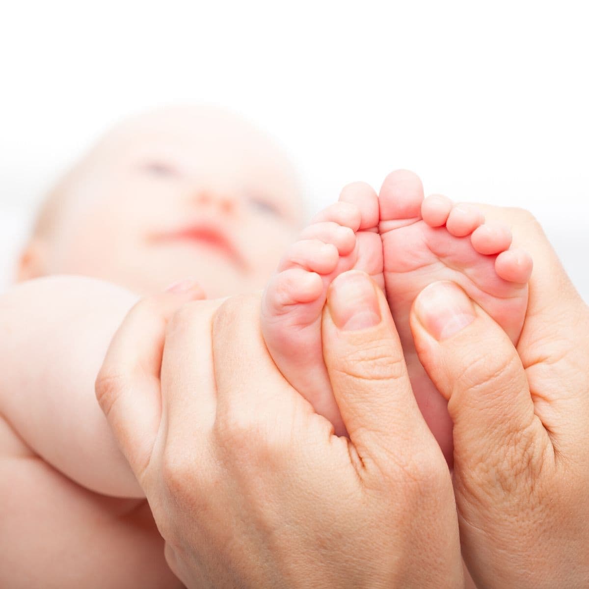 mother's hands holding infant baby's feet