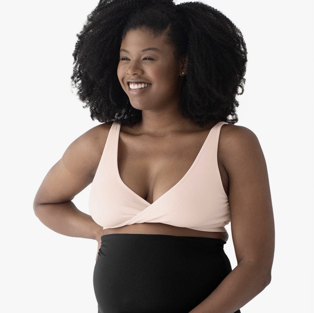 black woman in comfortable pink sleeping bra looking away from camera and smiling