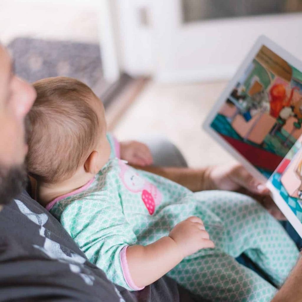father is reading a book to his baby