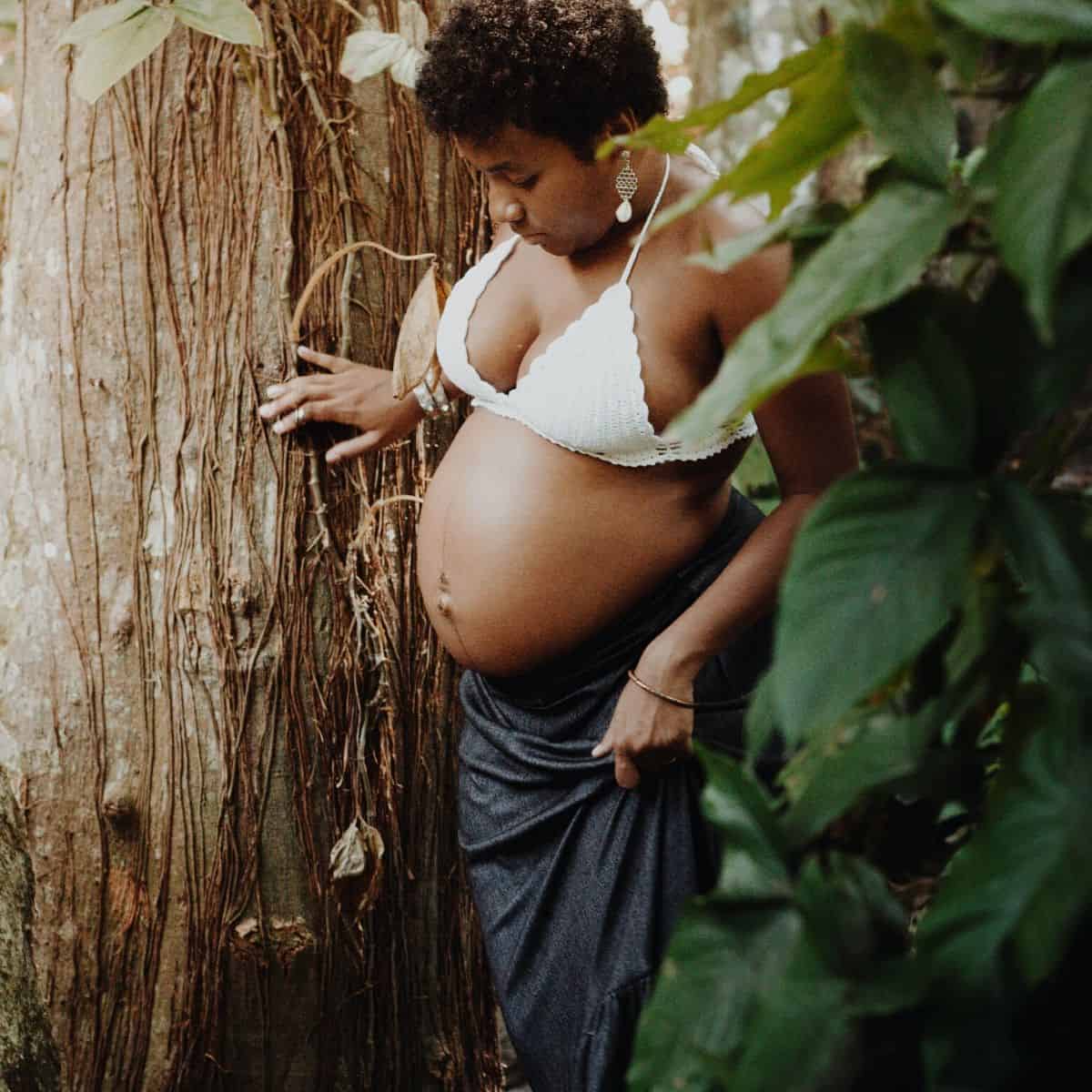 pregnant woman wearing a swimsuit and standing near a tree