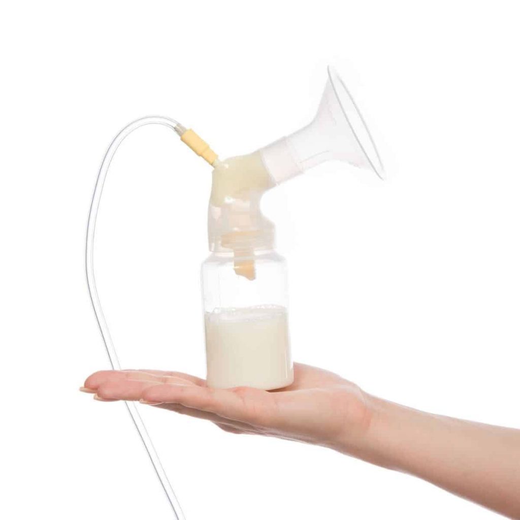 hand holding up a breast pump with the bottle filled with breast milk