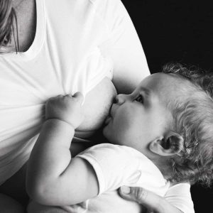 black and white photo of a baby breastfeeding