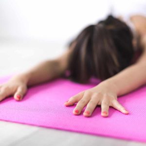 woman is stretching on a pink yoga mat
