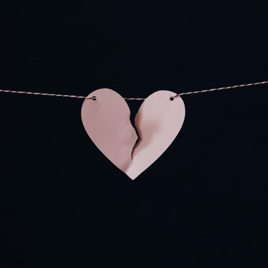 paper heart broken in half with string holding it up