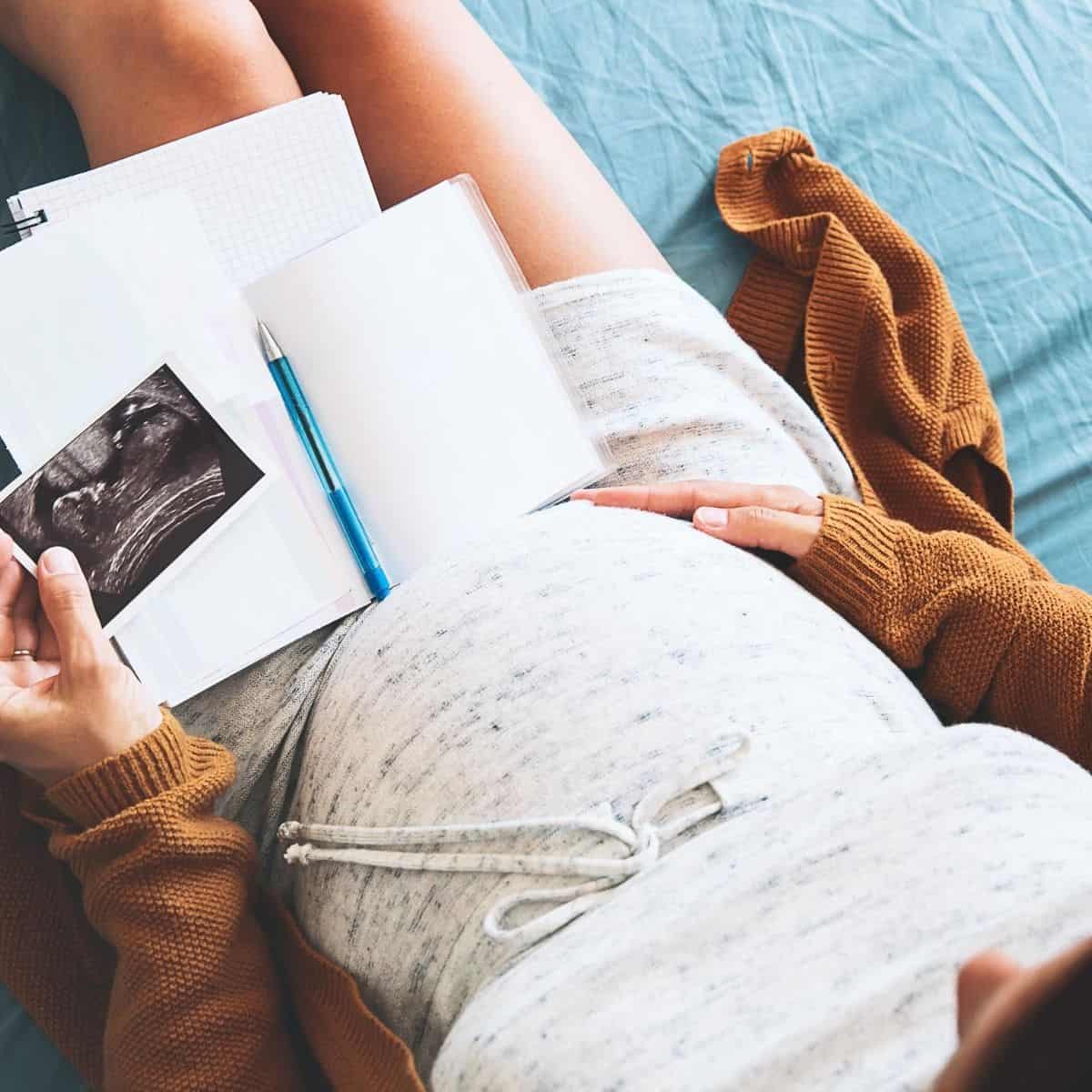 pregnant woman holding a notebook and picture of sonogram