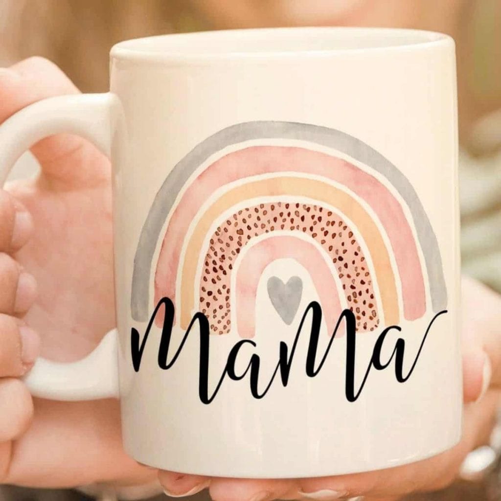 hands holding a mug that says mama with a rainbow and heart