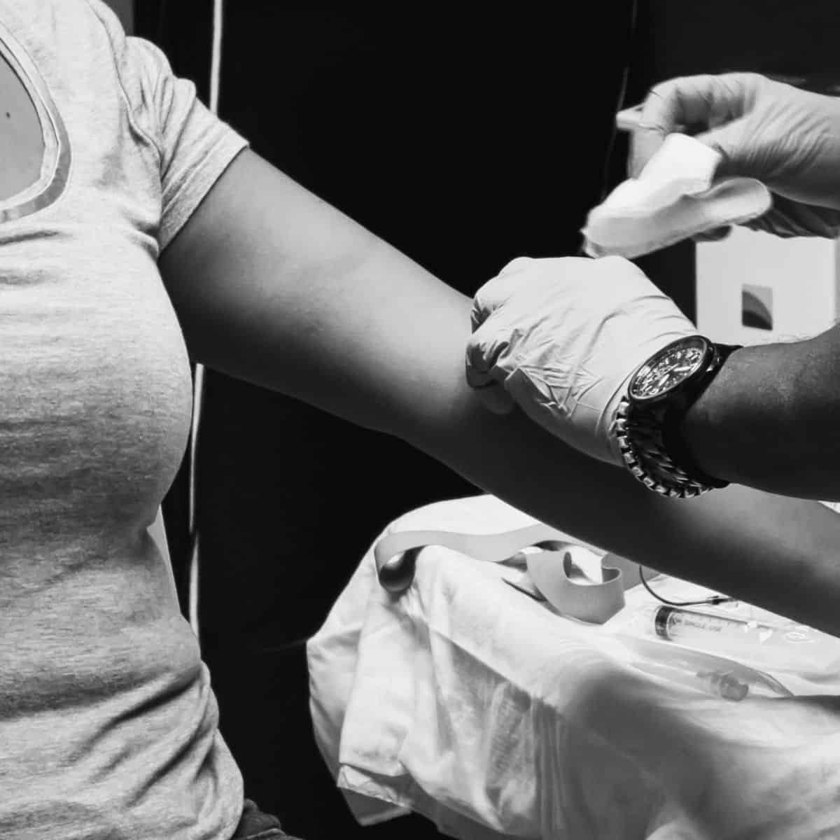 black and white photo of woman getting blood drawn from her forearm