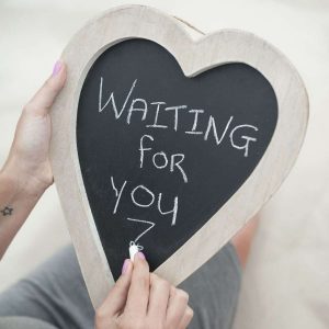 heart shaped chalkboard with someone writing "waiting for you"