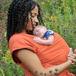 woman of color holding infant with baby wearing wrap