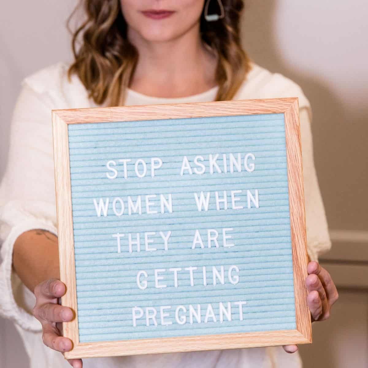 woman holding up letterboard that reads "stop asking women when they are getting pregnant"