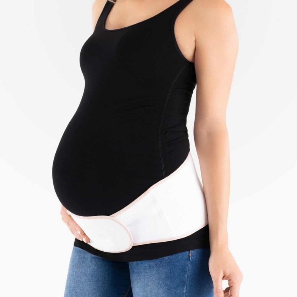pregnant woman standing sideways with one hand on her belly support band