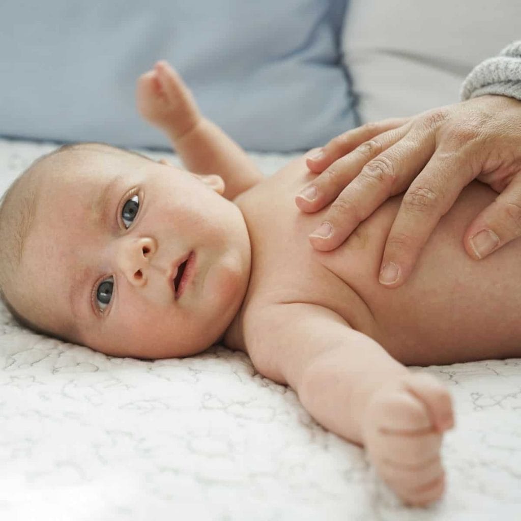 parent's hand is placed on baby's tummy in gentle, loving way