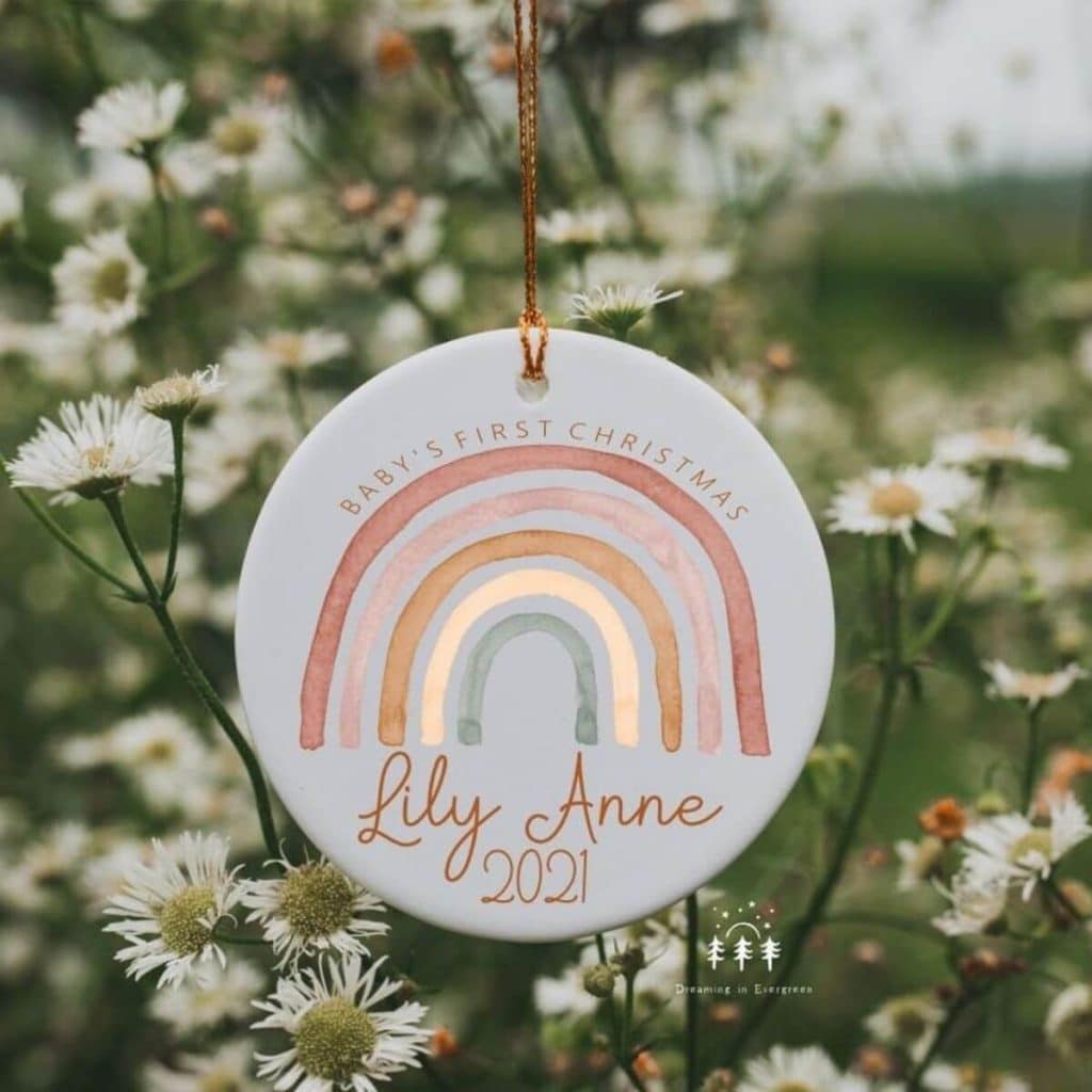 Christmas ornament hanging from tree with a rainbow and baby's name that says baby's first christmas