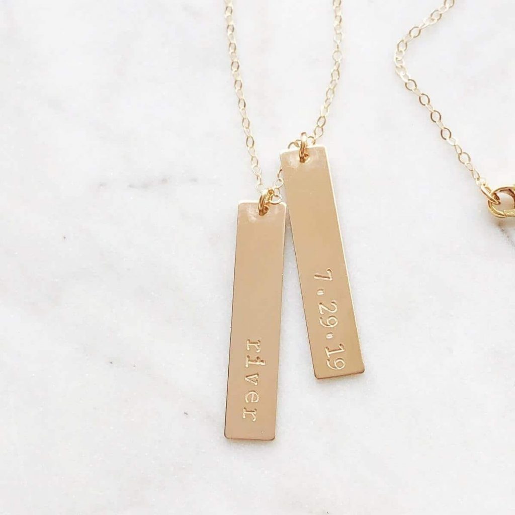 gold necklace on marble background with a bar with a person's name and a bar with a birth date