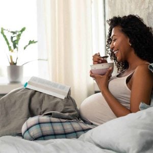 Pregnant woman reading and wearing maternity pajamas