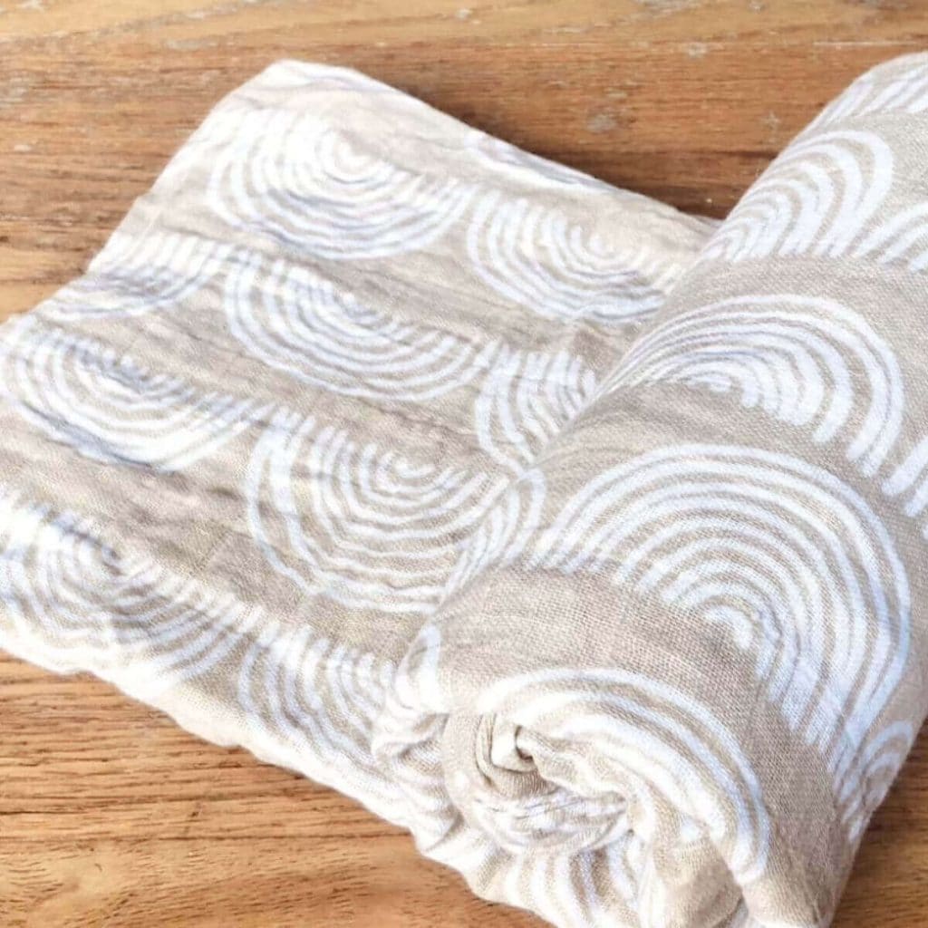 Light brown swaddle blanket with white rainbows