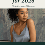 A Black woman with dark curly hair in a light blue silk camisole photographed against a moody blue-green painted backdrop. Text overlay reads "The Best Postpartum Pajamas for 2026. Tested by over 40k moms. Milk. Sweat. Blood. The 7 postpartum pajamas that survive it."