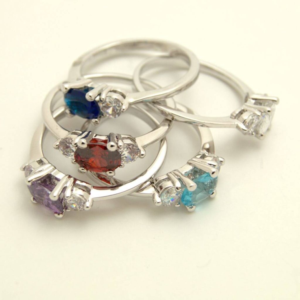 Silver rings with birthstones in them. The colors are sapphire, aquamarine, ruby, diamond, and amethyst.
