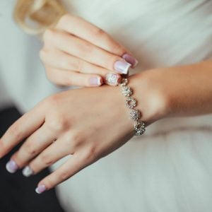 Woman's hands putting a silver bracelet made of rings with diamonds on it on her wrist