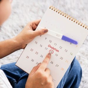 Woman holding a calendar with the 18th circled and the word ovulation over it
