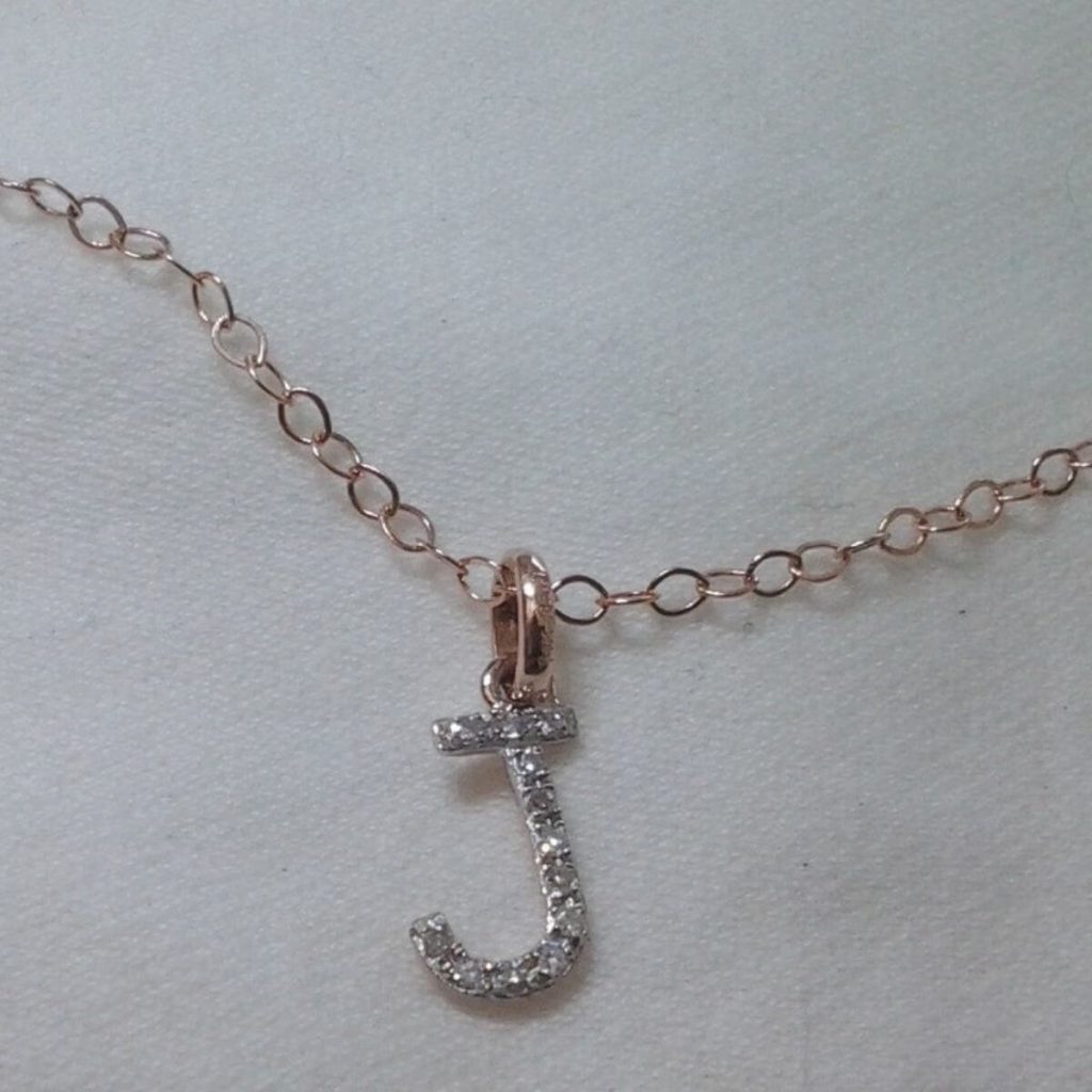 Gold link necklace chain with the letter "J" hanging from it in diamonds