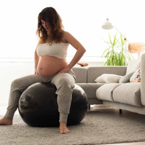 pregnant woman with legs spread sitting on birthing ball