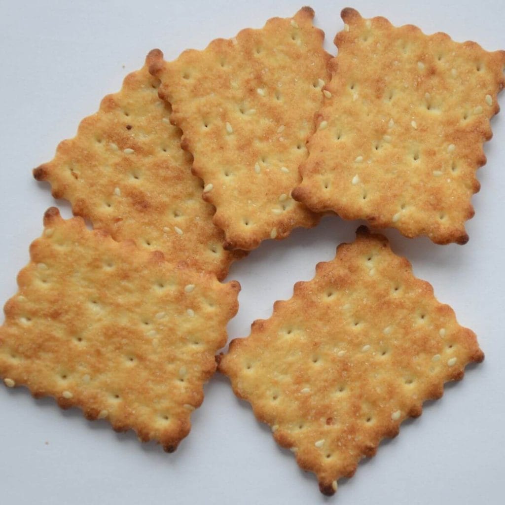 Five crackers sit on an all white table top.
