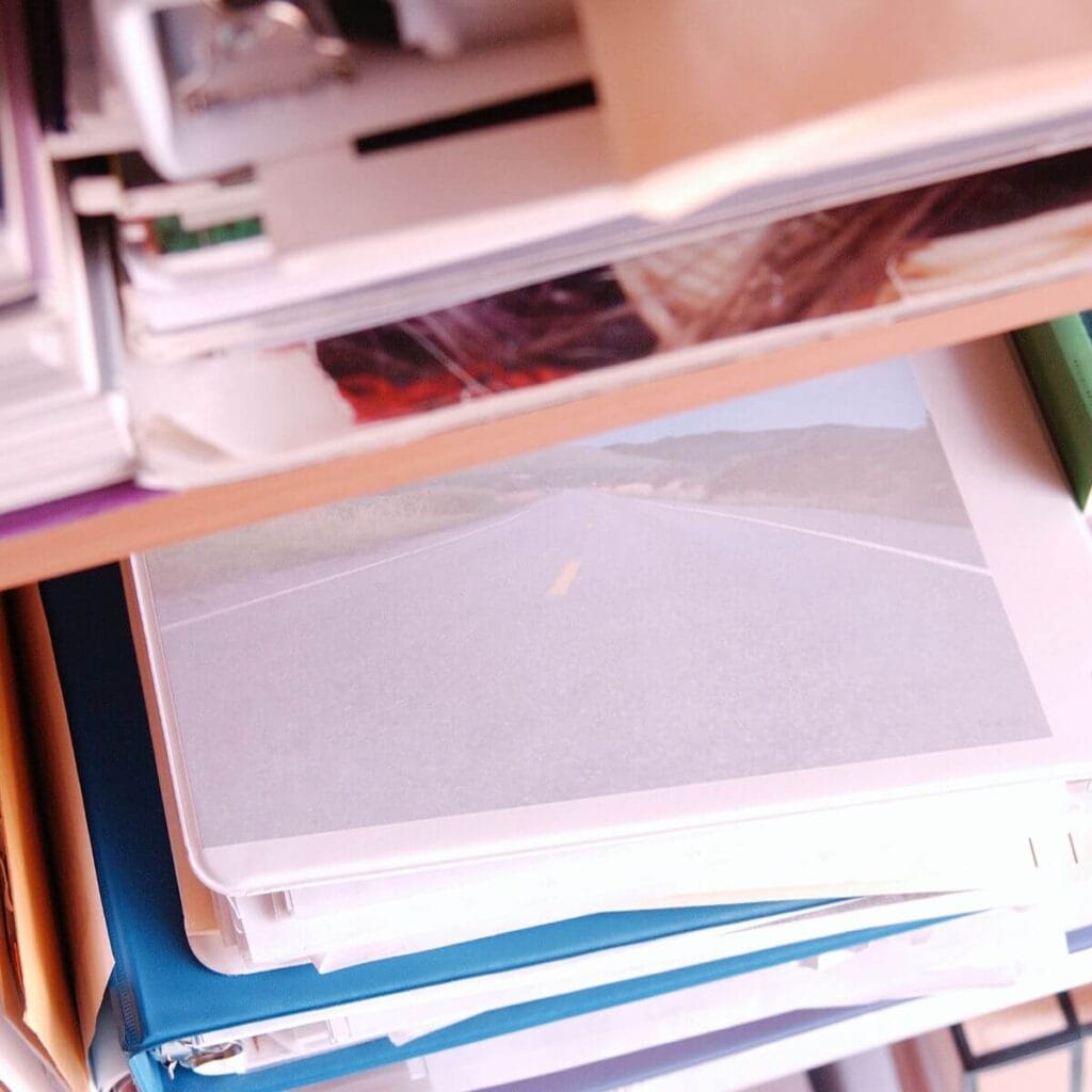 A shelf with papers, notebooks, binders and folders is full to the max and spilling out.