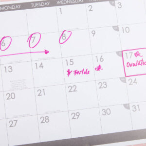 There is a calendar in the photo. There are 3 dates circled, the word "fertile" in the box for the 15th, and the box for the 17th is outlined in pink with the word "ovulation" written in it.