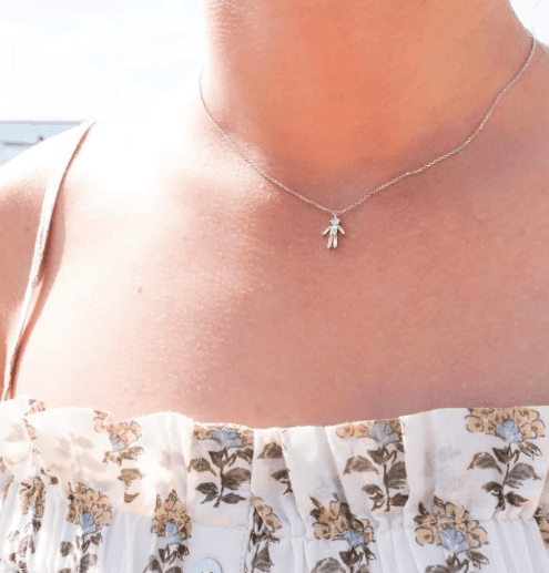 Woman wearing a tank top and a diamond baguette child figure necklace in white gold