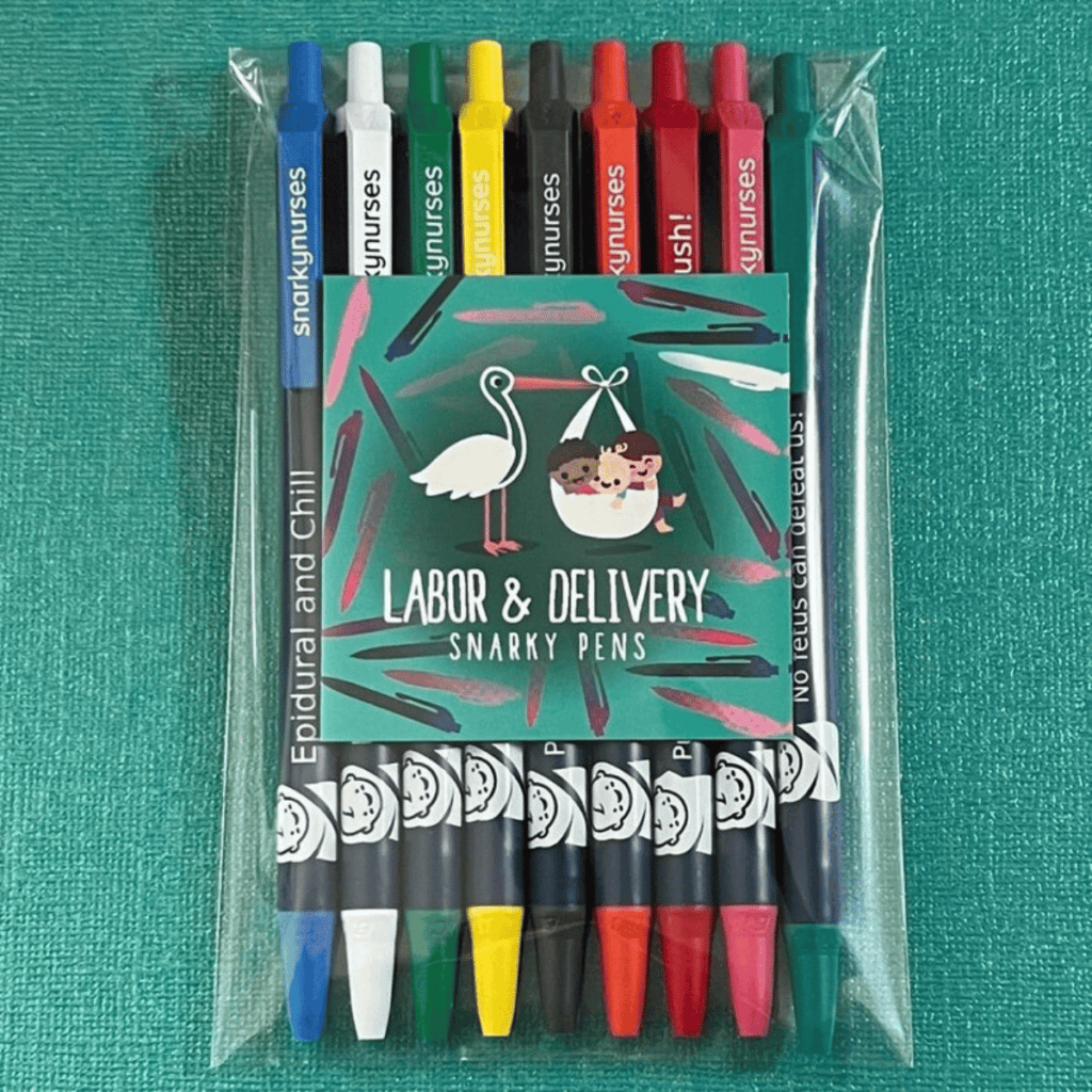 The image features a pack of multicolored pens each with a cap and a white body, which are labeled with humorous, nursing-related phrases. The phrases are partially visible and seem to play on medical terms, for example, "Epidural and Chill." The packaging card has a quirky design with a stork carrying a baby and the words "LABOR & DELIVERY SNARKY PENS." The background is a vibrant teal fabric, creating a lively contrast with the pens. This product seems designed to bring a bit of humor and lightness to a hospital setting.