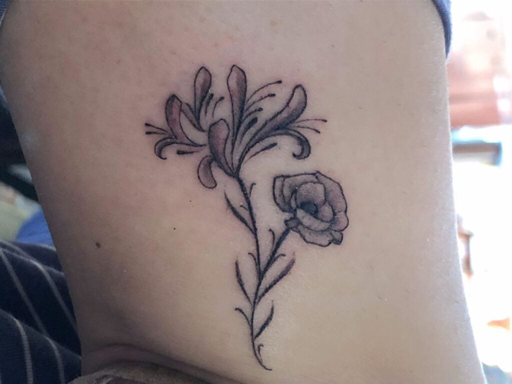 Black and white tattoo of a small poppy and a honeysuckle branch